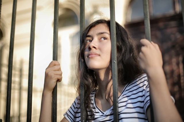 sad-isolated-young-woman-looking-away-through-fence